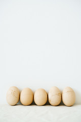 five Easter eggs trendy pastel colored with cracked shells on a white table against a white wall. minimal style. Easter concept.copy space for text