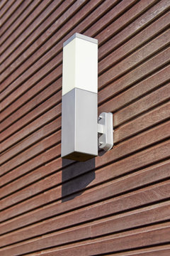 Exterior lamp against a padouk wooden wall