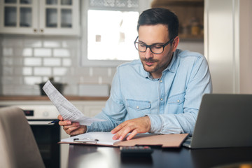 Young businessman working from home while holding a sketch in his hand.