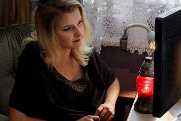 Young woman in mourning is looking on computer screen. Sad girl in black is watching funeral live stream.