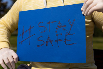 Stay safe sign on blue chroma key paper held by a man in surgical gloves