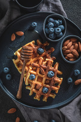 Fototapeta premium Tasty waffles with honey, blueberries and almont