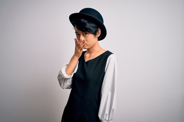 Young beautiful asian girl wearing casual dress and hat standing over isolated white background...