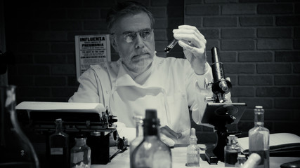 Black and white of a medical scientist from the year 1918 in a private laboratory during the influenza pandemic labeled the Spanish Flu looking at a blood sample.