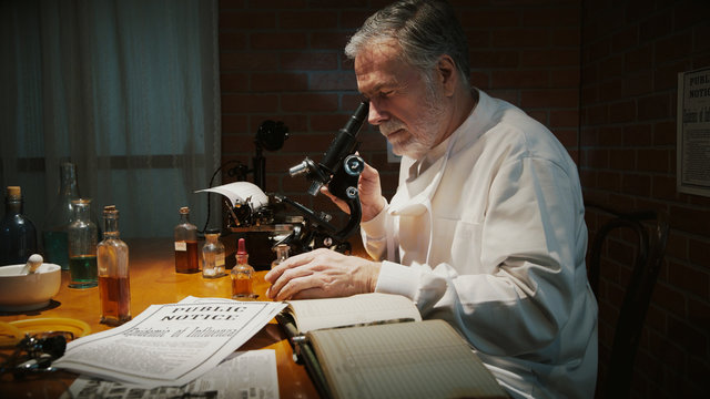 A Scientist In His Laboratory During The 1918 Influenza Pandemic Called The Spanish Flu Documents Looks Through A Microscope At A Sample.