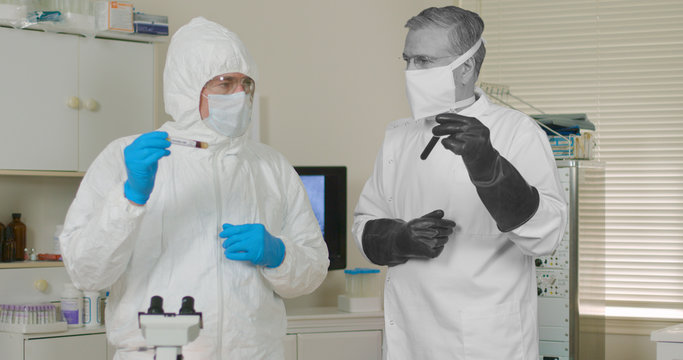 Scene With Two Medical Research Scientists One From The Present And One From The Past Both In Full PPE Garb Dealing With Pandemics.