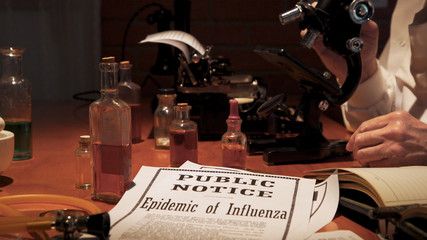 Notice of the influenza epidemic of the year 1918 lying on the laboratory table of a medical research scientist studying the virus. - obrazy, fototapety, plakaty