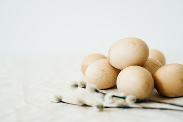 several Easter eggs of a fashionable pastel color with cracks lie on the table on a light tablecloth with branches of a budding willow. minimal style.Easter concept.copy space for text