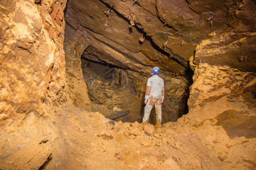 Miner explorer in abandoned bauxite ore mine tunnel board-and-pillar work cavity