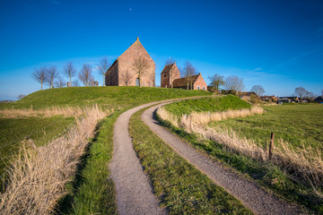 Landscape view on medieval church of the village Ezinge in the Dutch landscape of the province of Groningen