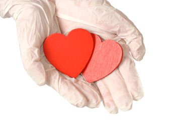 Two red hearts in hand with rubber gloves isolated on white