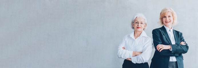 Senior business women. Wisdom experience leadership. Female partners standing with arms folded.