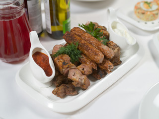 Roasted meat assortment with red and white sauce on a plate