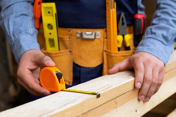 Carpenter's hands measuring plank