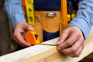 Carpenter's hands measuring plank