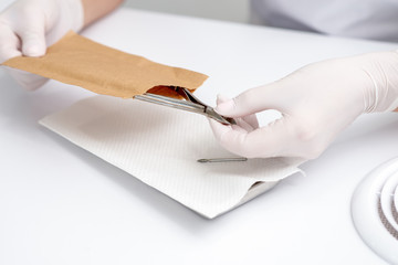 Hands taking manicure tools from craft envelope before manicure procedure.