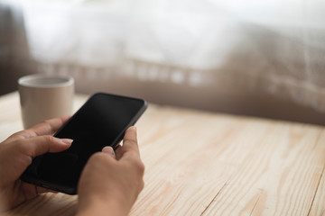 The girl's hand uses a mobile phone to work at home with a cup of coffee on desk.