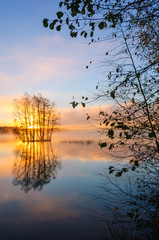Obraz na płótnie Canvas Sun shining through a little island. Lake Finnsjön, Sweden.