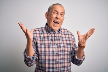 Naklejka premium Senior handsome man wearing casual shirt standing over isolated white background crazy and mad shouting and yelling with aggressive expression and arms raised. Frustration concept.