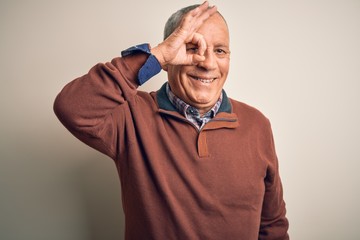 Senior handsome man  wearing elegant sweater standing over isolated white background doing ok gesture with hand smiling, eye looking through fingers with happy face.