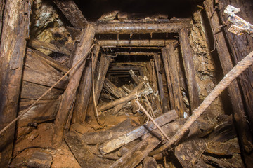 Underground abandoned bauxite ore mine tunnel with collapsed wooden timbering
