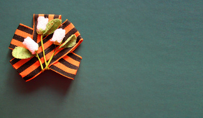 Concept background of May 9, 2020 - 75 years of Victory in the Great Patriotic War. Handmade flowers on St. George's ribbon. Isolated on green background. Memorial day. Greeting card. Copy space