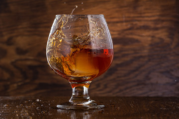 Splash in cognac glass from falling ice