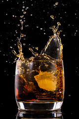 Splash in a glass from falling ice on a black background