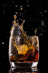 Splash in a glass from falling ice on a black background