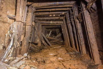 Underground abandoned bauxite ore mine tunnel with collapsed wooden timbering