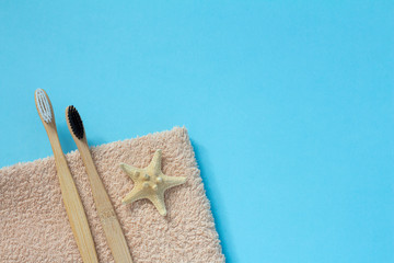 Bamboo toothbrushes, starfish and towel on a blue background top view. Zero plastic concept