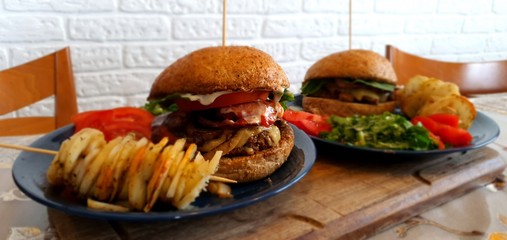 Burger with bacon, potatoes and vegetable salad