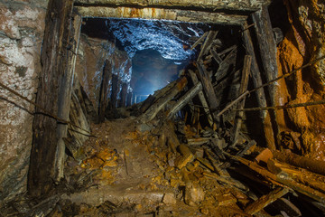 Underground abandoned bauxite ore mine tunnel with collapsed wooden timbering