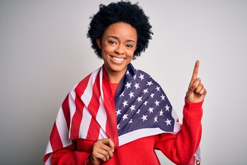 Young African American afro woman with curly hair wearing united states of america flag surprised with an idea or question pointing finger with happy face, number one