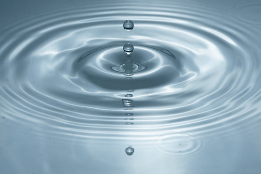 Water drops splash in a glass grey colored