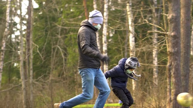 Outdoor games with children in nature during the quarantine of the coronovirus Covid 19. A family in medical masks and gloves to protect against infection. Favorite football game.