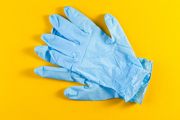 A pair of new blue latex protective gloves isolated on a yellow background. Blue surgical gloves. Concept of medicine health care.