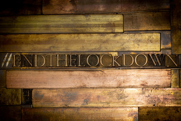 Photo of real authentic typeset letters forming hashtag End The Lockdown text on vintage textured...