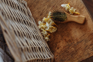 wooden comb on a wooden chair with dry flowers white and yellow and a wooden basket