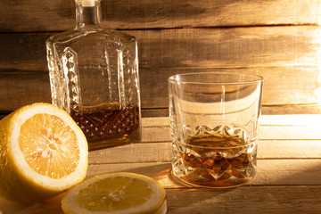 Cognac in decanter and lemon on a wooden background