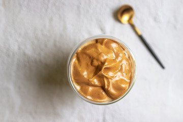 Dalgona Coffee; fluffy whipped coffee on milk. Coffee is a beverage made by whipping equal proportions of instant coffee, sugar and hot water until it becomes creamy. Top view