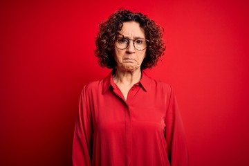 Fototapeta na wymiar Middle age beautiful curly hair woman wearing casual shirt and glasses over red background depressed and worry for distress, crying angry and afraid. Sad expression.