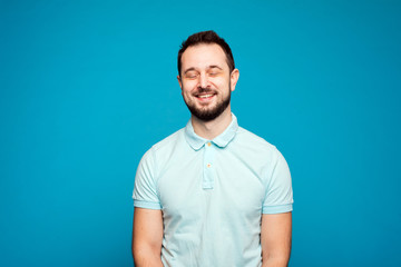 man with a beard laughs with closed eyes, joy. A handsome young man smiling