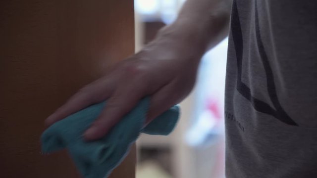 hand disinfecting a doorknob with cloth and spray