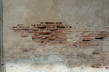 Red broken bricks wall with metal pipe. Old shabby concrete.