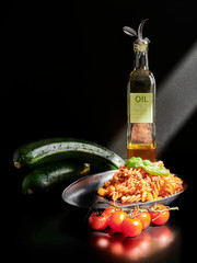 Chickpeas fusilli with cherry tomatoes, zucchini, linseed and olive oil, on a black background with...