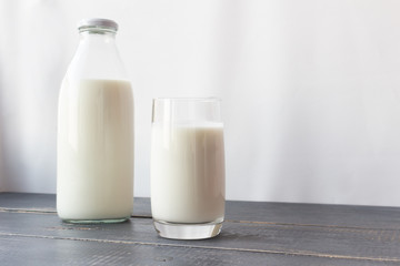 Fermented dairy products. Milk, kefir in a glass bottle and a glass. Farm rustic drinks on a gray wooden background.