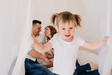 Cute kid daughter and dad tickling mom having fun good time playing together at home, happy parents...