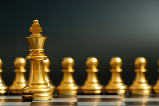 Gold king chess piece stand in front of pawn on black background (Concept of leadership, management)