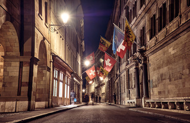 Fototapeta premium Historic street with stone buildings at night in Geneva.